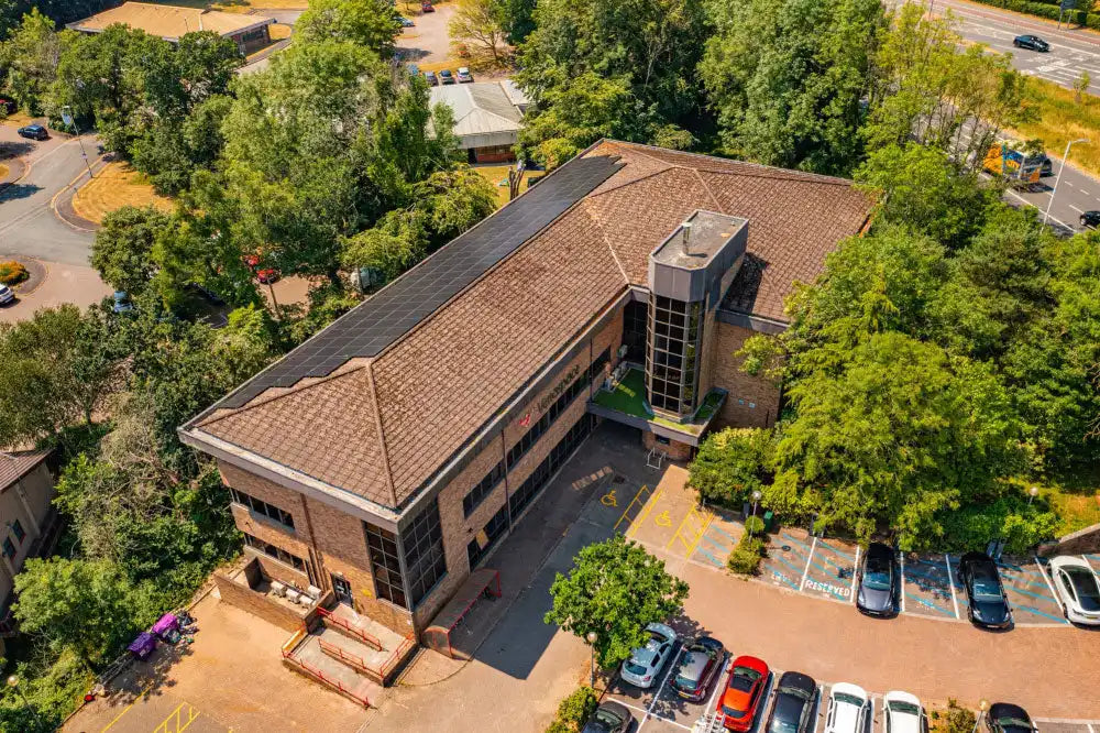 Two-story commercial office building with brown shingle roof and glass accents.